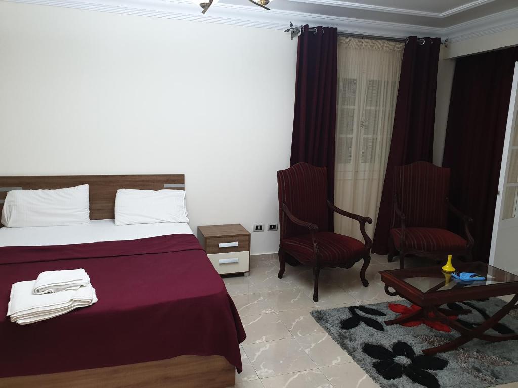 um quarto de hotel com uma cama e duas cadeiras em Khaled Ibn Al Waleed Apartment by Alexander the Great Hotel em Alexandria