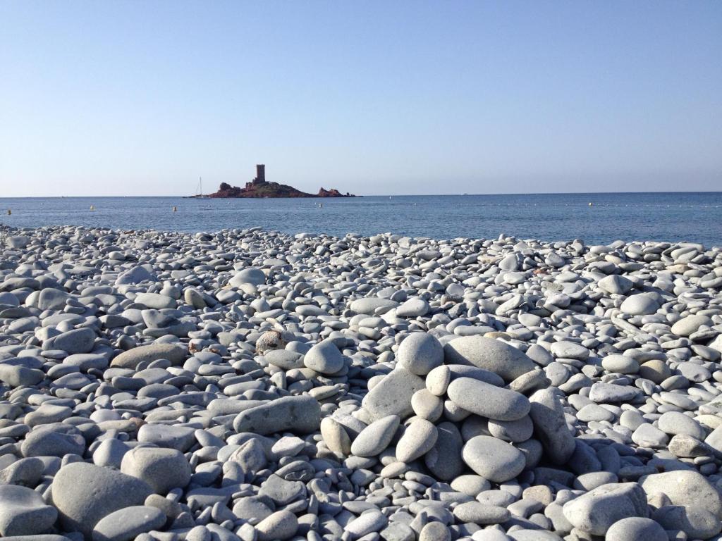 a large group of rocks on a beach with a lighthouse at Appartement Vacances ZEN in Fréjus