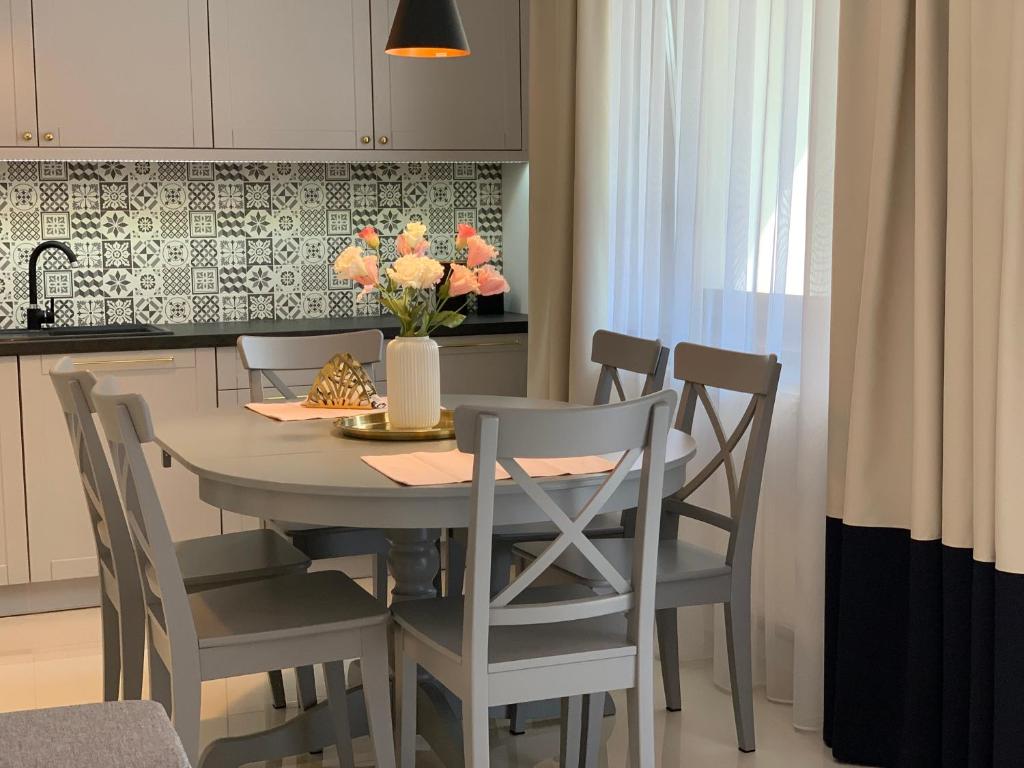 uma cozinha com uma mesa com cadeiras e um vaso de flores em Apartament Zacisze Rose Gold em Malbork