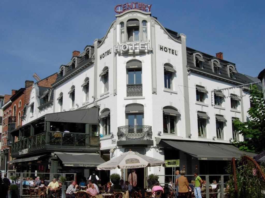 a large white building with people sitting outside of it at Hotel The Century in Hasselt