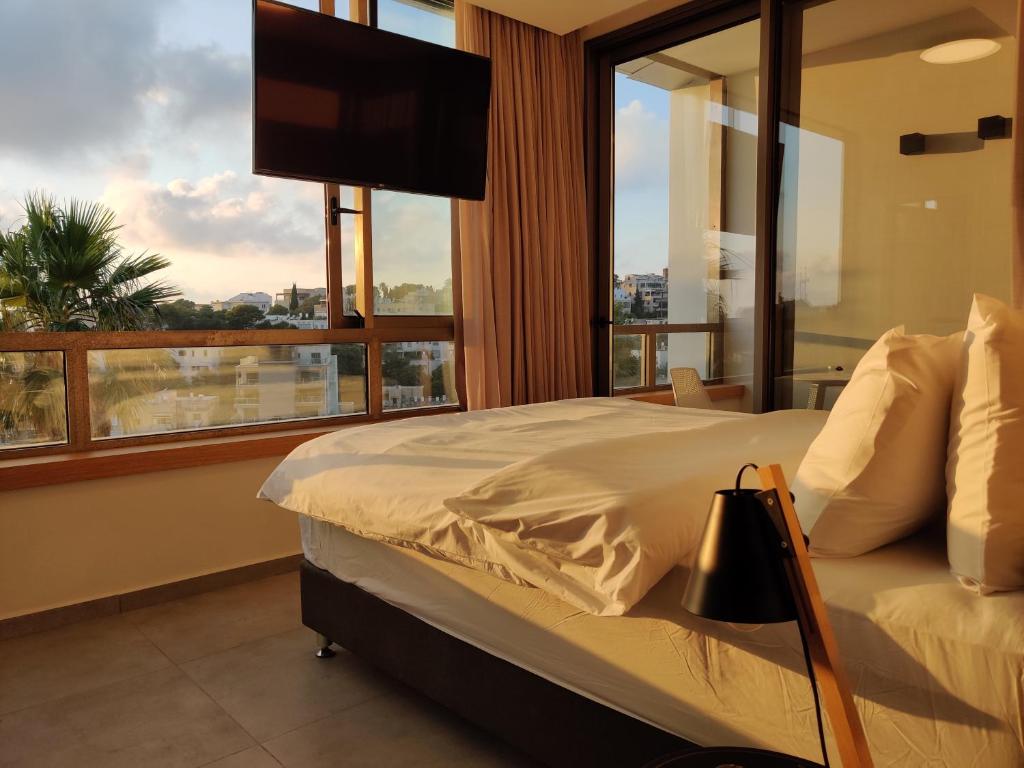 a bedroom with a bed and a large window at Luxury Suites by Notaly Ariel in Haifa