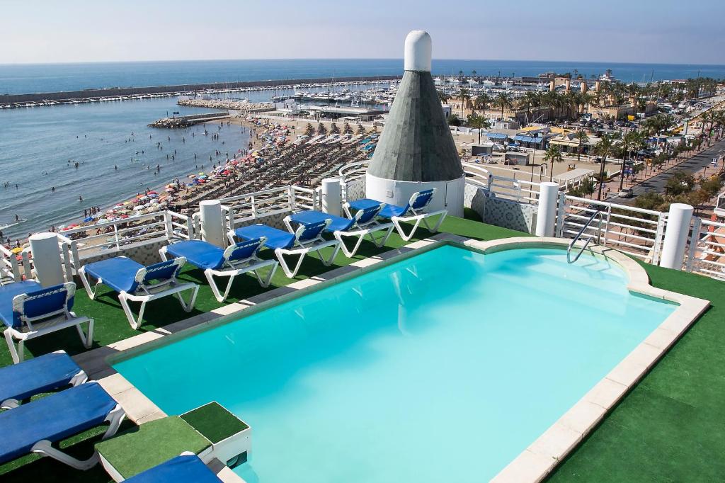 a swimming pool with chairs and a view of the beach at Hotel Villa de Laredo in Fuengirola