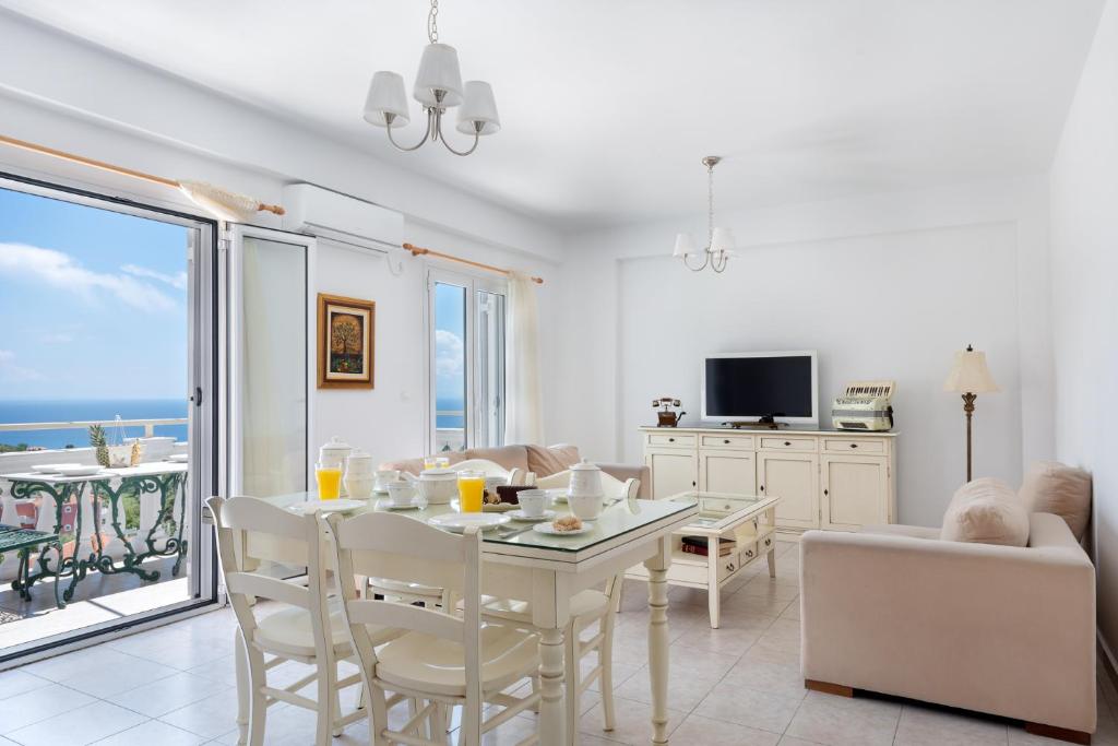un soggiorno con tavolo, sedie e vista sull'oceano di Pernari Apartments a Spartià