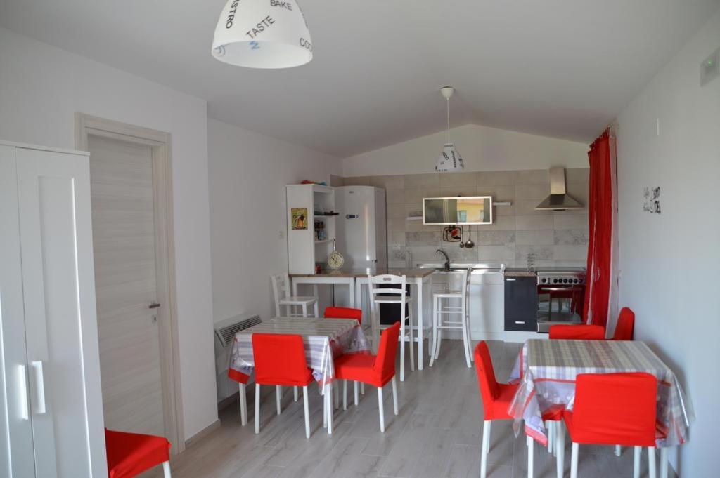a kitchen and dining room with red chairs and a table at La Maison di Sara in Santa Maria La Carità