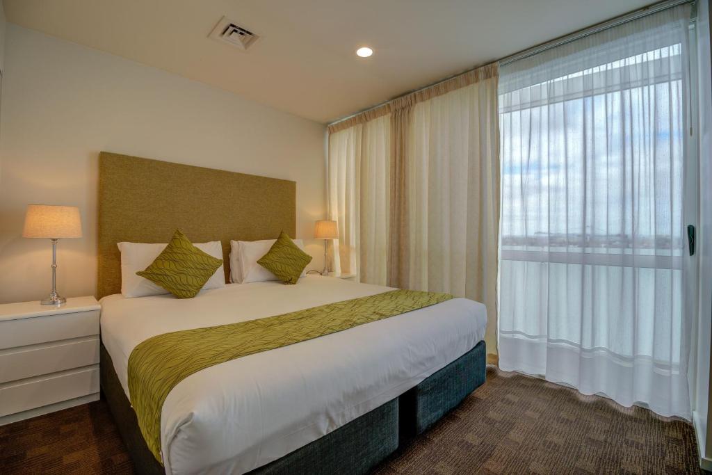 a bedroom with a large bed and a large window at The Quadrant Hotel & Suites in Auckland