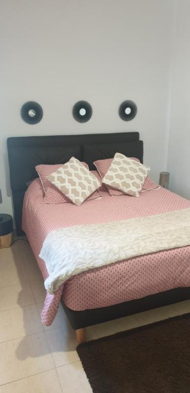 Una cama con almohadas rosas y blancas. en Sweet home en Kenitra