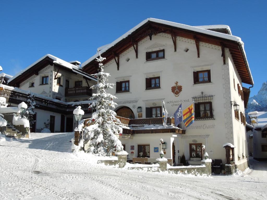 un bâtiment dans la neige avec un sapin de Noël devant dans l'établissement Schlosshotel Chastè, à Tarasp