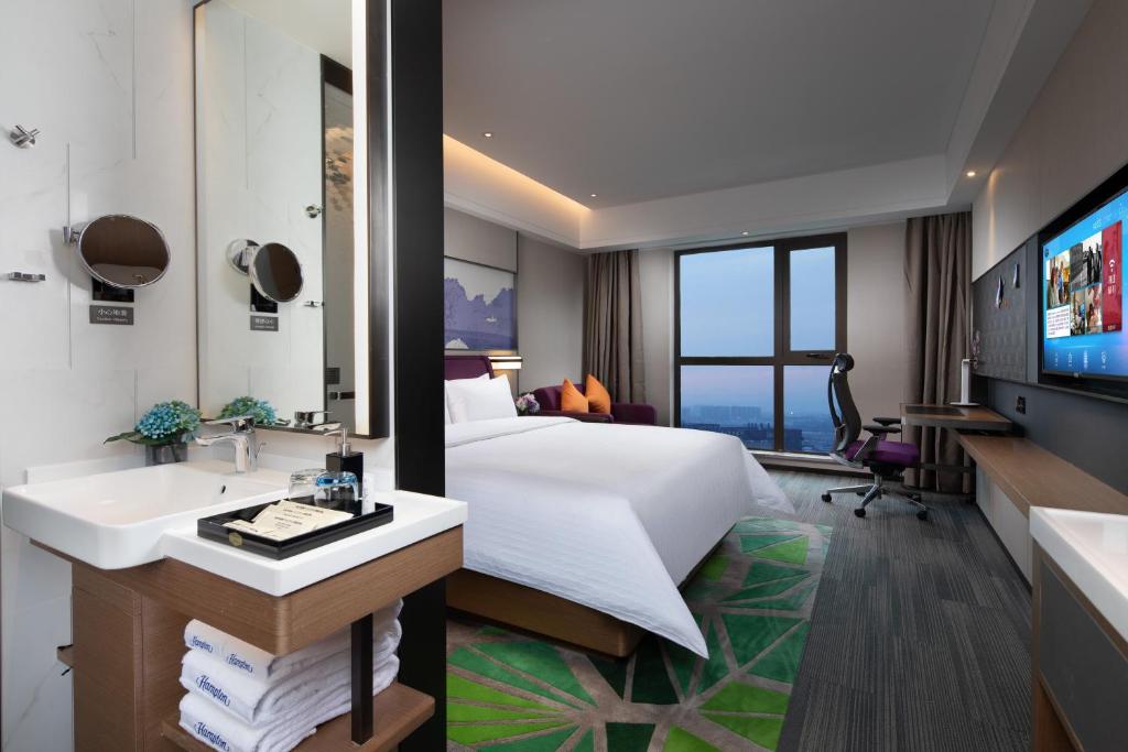 a hotel room with a bed and a sink at Hampton by Hilton Yixing Renmin Middle Road Branch in Yixing