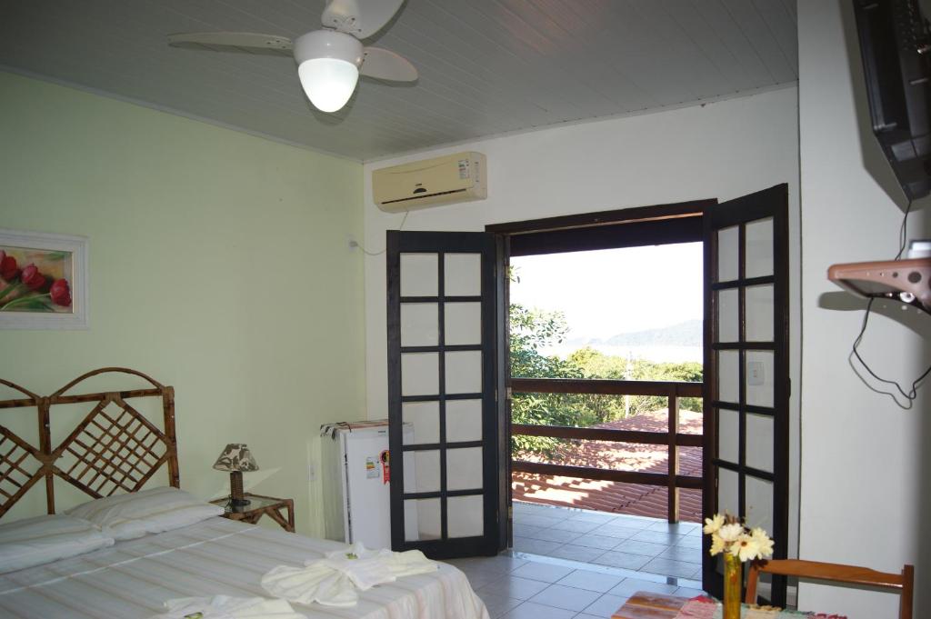 a bedroom with a bed and a door to a balcony at Pousada Costa dos Corais in Mangaratiba