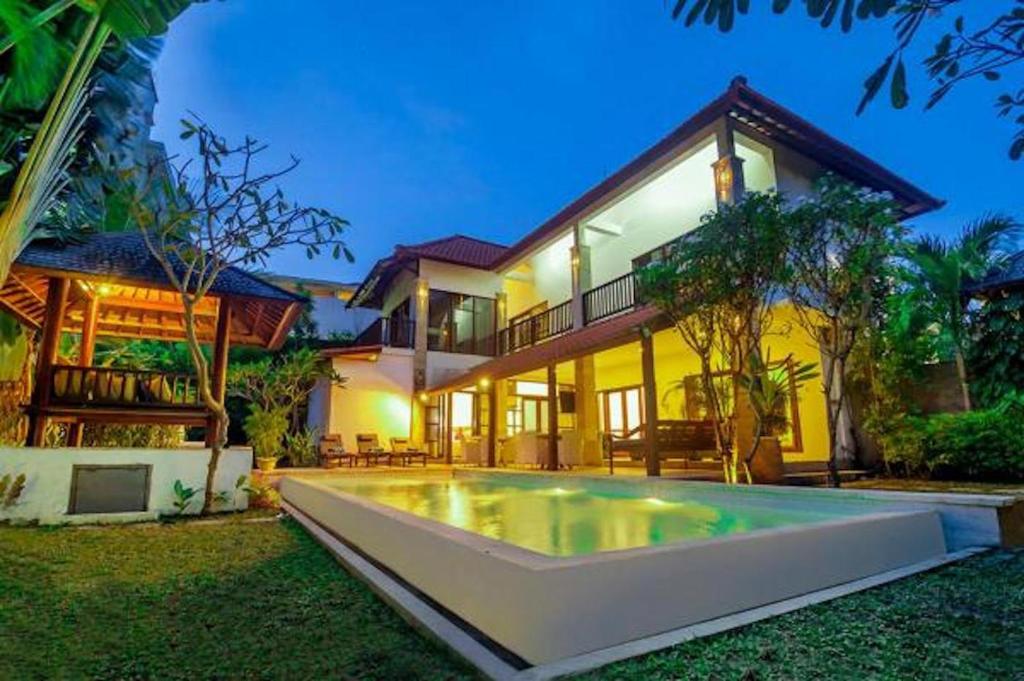 a large house with a swimming pool in front of it at Mawar Estate in Seminyak
