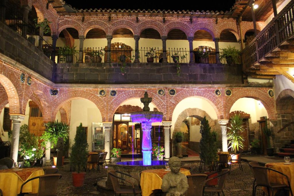 a room with a fountain in a building with tables at Hotel Marqueses in Cusco