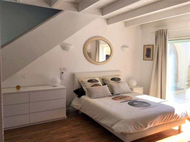 a white bedroom with a bed and a mirror at Appartements Les Pesquiers 2 Hyères Plage in Hyères