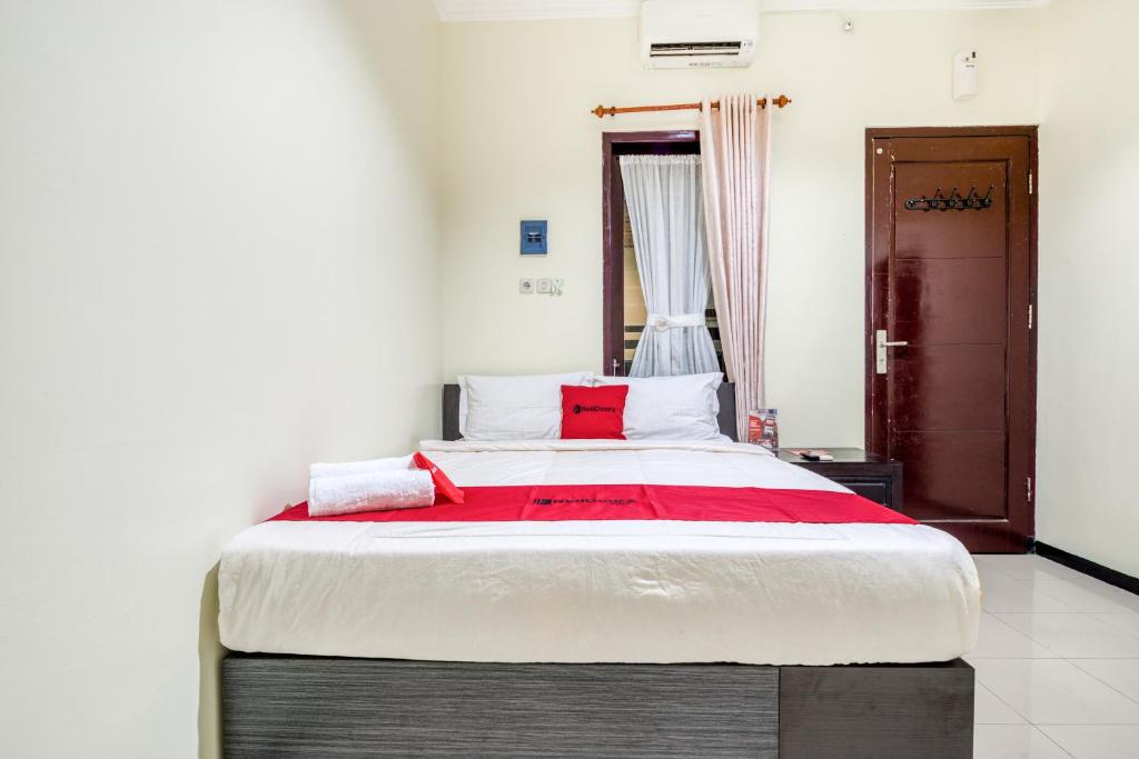 una camera da letto con un grande letto con cuscini rossi di RedDoorz Syariah @ Ketintang Surabaya a Surabaya