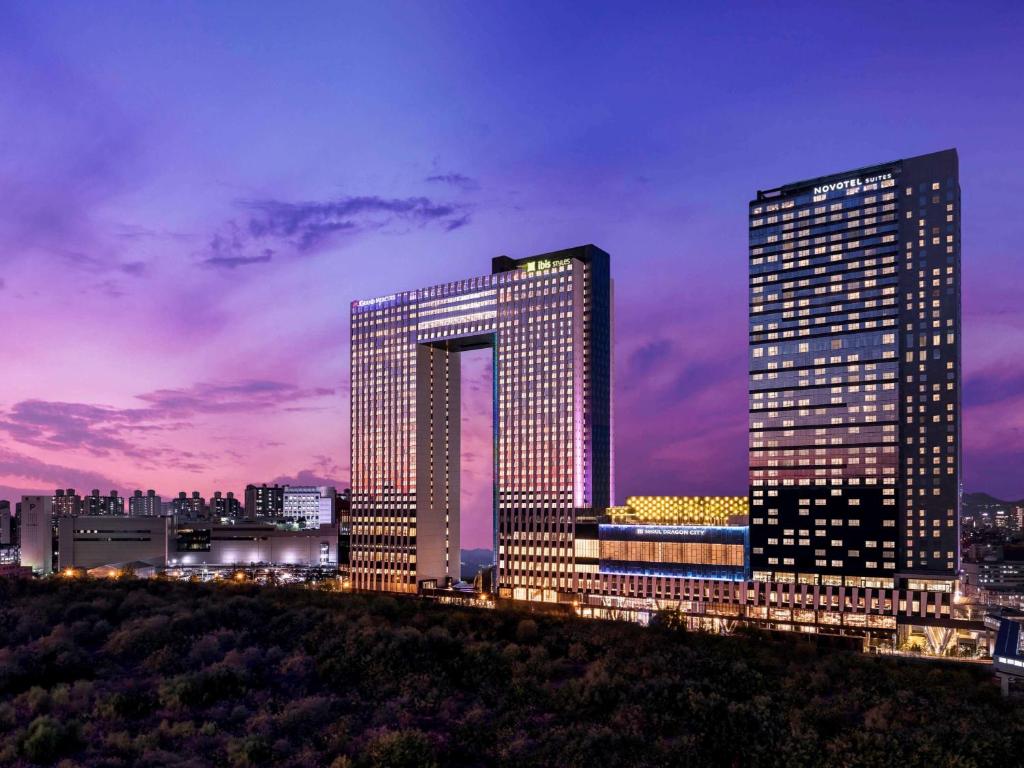 two tall buildings in a city at night at Novotel Ambassador Seoul Yongsan in Seoul