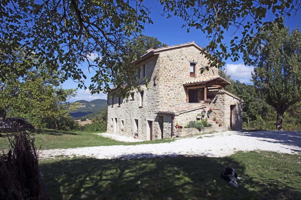 an old stone house on a grassy field at B&B BOSCOVECCHIO in Assisi
