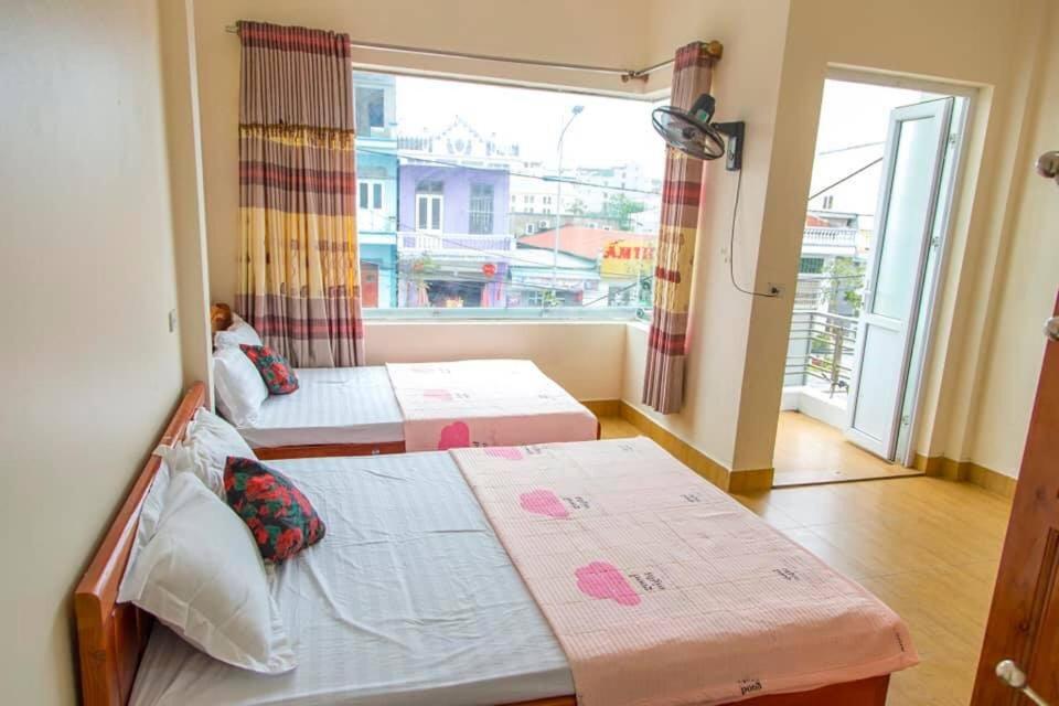 two beds in a room with a large window at I Love Coto Hai Au Hotel is central near beach in Đảo Cô Tô
