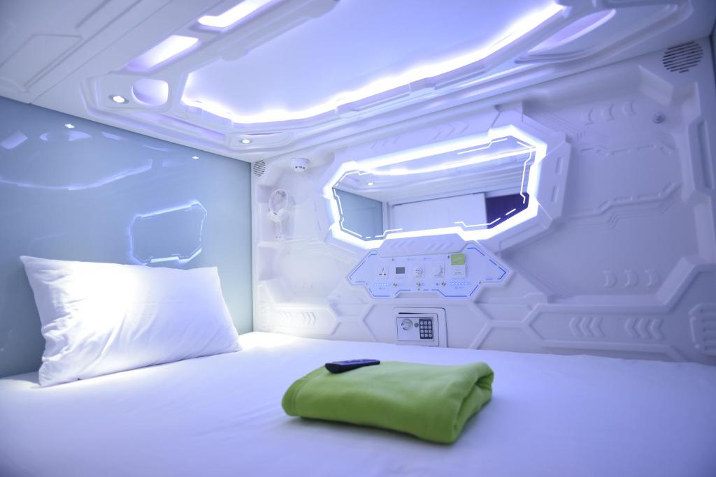 a bedroom with a white bed with a green pillow at Whiz Capsule Hotel Thamrin Jakarta in Jakarta