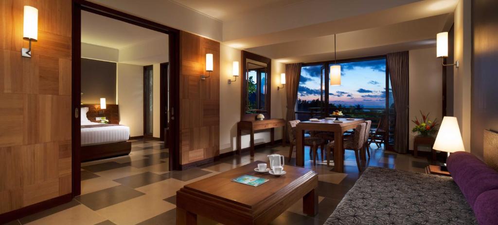 a living room with a room with a bed and a table at Sun Island Hotel & Spa Kuta in Kuta