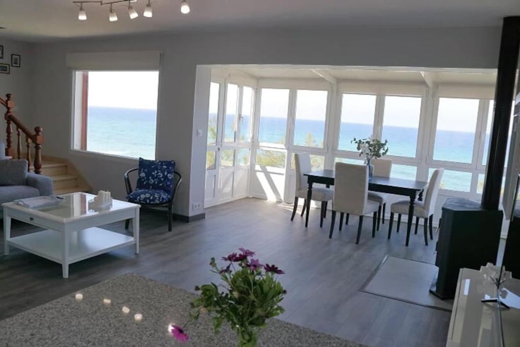 un soggiorno con tavolo, sedie e vista sull'oceano di Playa Catedrales Village a Barreiros