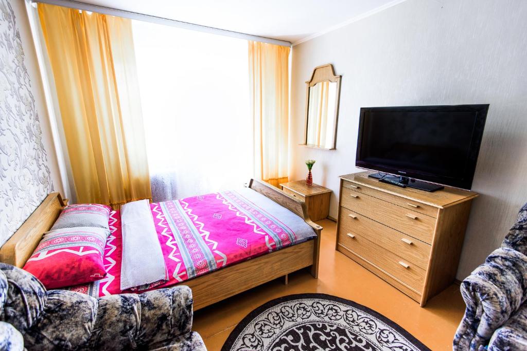 a bedroom with a bed and a flat screen tv at Квартира на Козлова 13 in Salihorsk