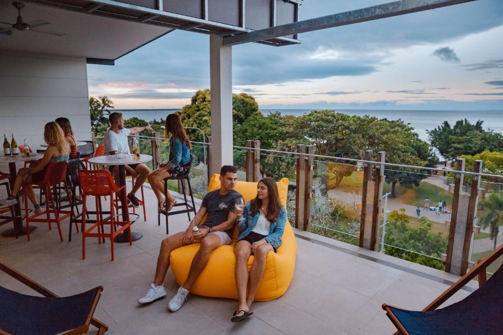 un grupo de personas sentadas en una silla de bolsa de frijoles en un balcón en Global Backpackers Cairns, en Cairns