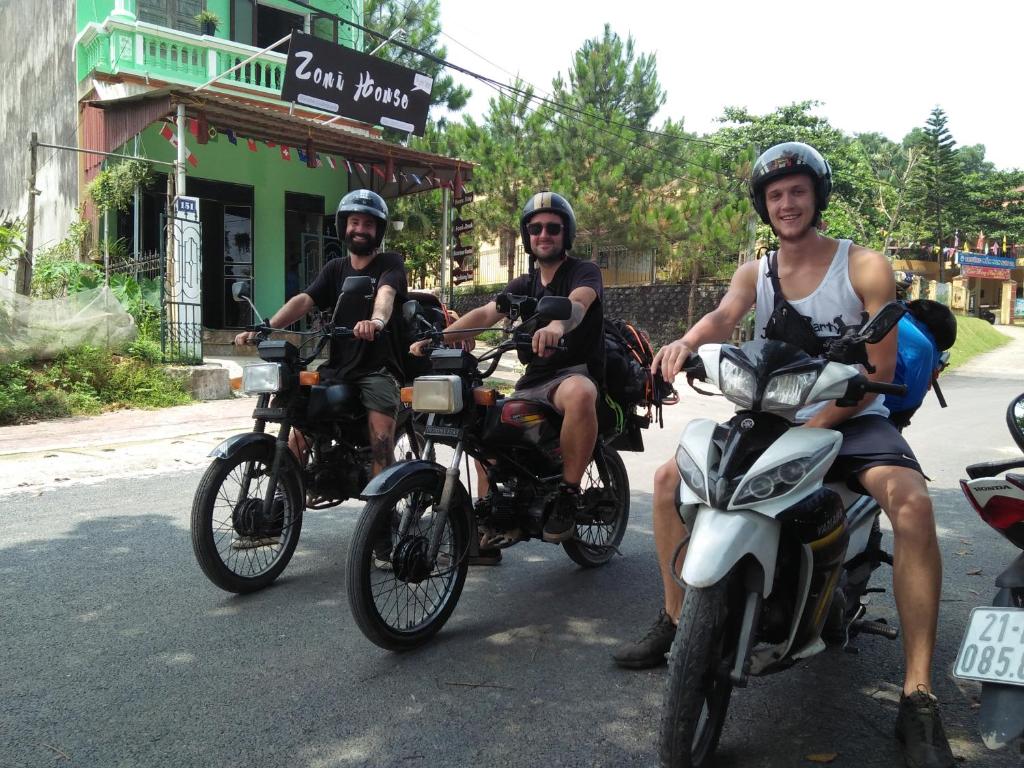 three men are riding motorcycles down a street at Zoni House-Yen Bai in Xóm Soi (2)