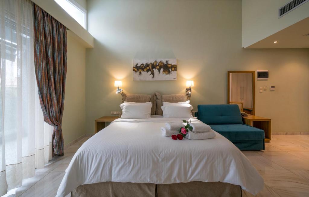 ネア・ペラモスにあるEdem Luxury Apartmentsのベッドルーム(白い大型ベッド1台、青い椅子付)