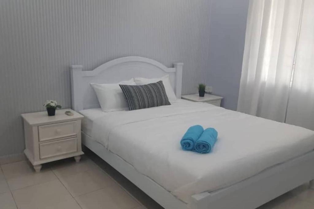 ein weißes Bett mit blauen Hausschuhen darauf in der Unterkunft MELAKA HOMESTAY in Malakka