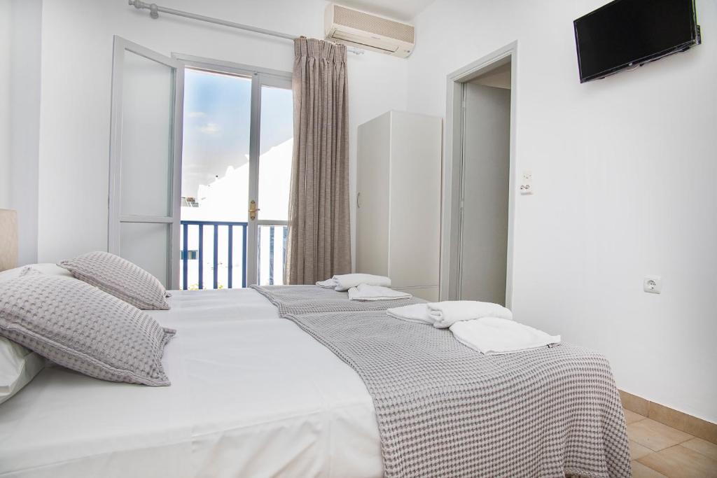 2 Betten in einem Zimmer mit einem großen Fenster in der Unterkunft LALOS Rooms in Parikia