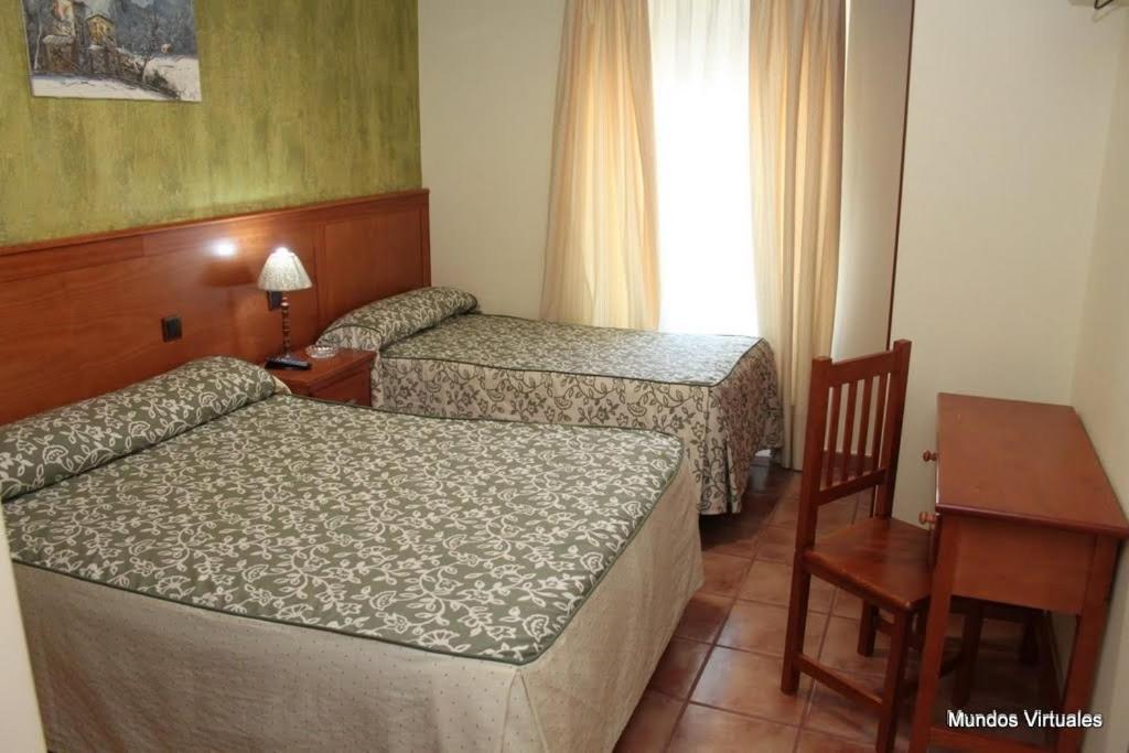 Habitación de hotel con 2 camas, mesa y escritorio en Nuevo Hostal Paulino en Trujillo