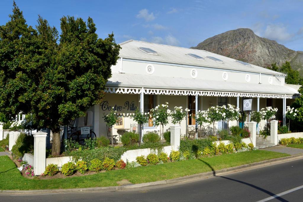 ein weißes Haus mit einem Berg im Hintergrund in der Unterkunft Centre-Ville Guest House in Franschhoek