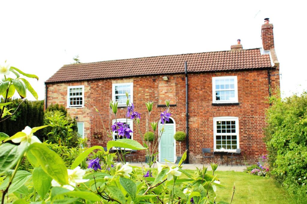 a brick house with a green door and flowers at The Vine B & B in South Thoresby