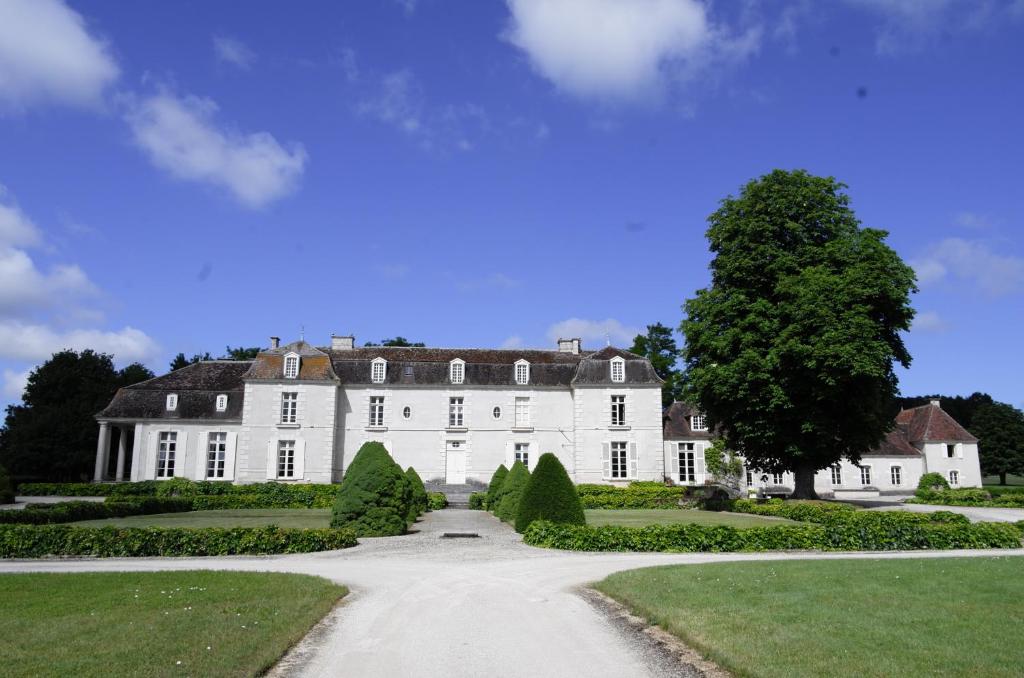 ein großes weißes Haus mit einem Baum und einer Auffahrt in der Unterkunft Château de Villemorien in Villemorien