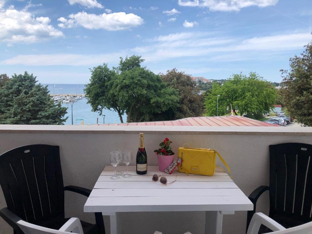 a white table with a bottle of wine and two glasses at Apartments La Playa in Pula