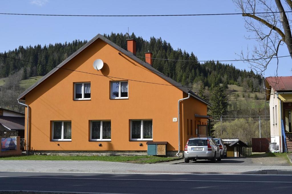 ein orangenes Haus mit einem davor geparkt in der Unterkunft Apartmán Karolinka 109 in Karolinka