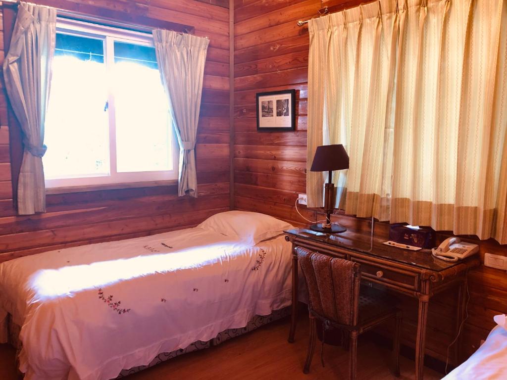 a bedroom with a bed and a desk and a window at Cingjing Hanging Garden &amp; Resort in Ren&#39;ai