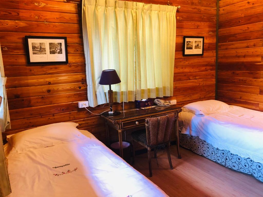 a room with two beds and a desk in a cabin at Cingjing Hanging Garden &amp; Resort in Ren&#39;ai