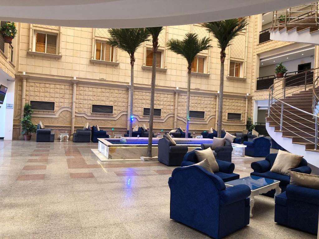 a lobby with blue couches and palm trees in a building at رواسي الفخامة للشقق الفندقية in Taif