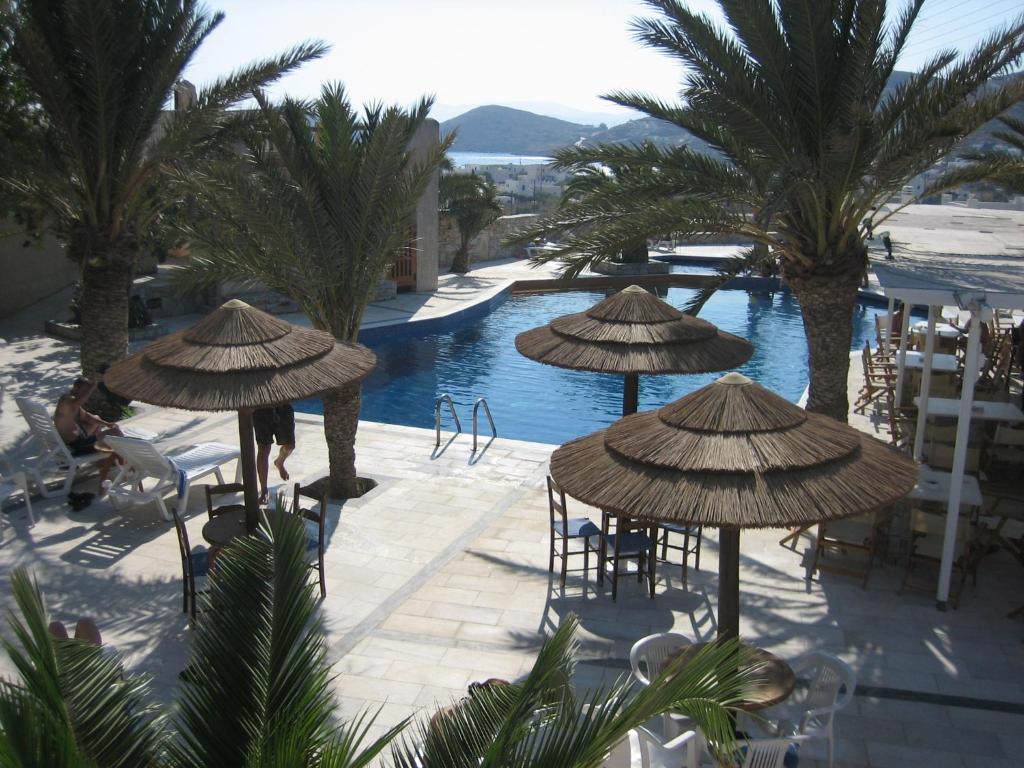 een resort met een zwembad met palmbomen en parasols bij Homer's Inn Hotel in Ios Chora