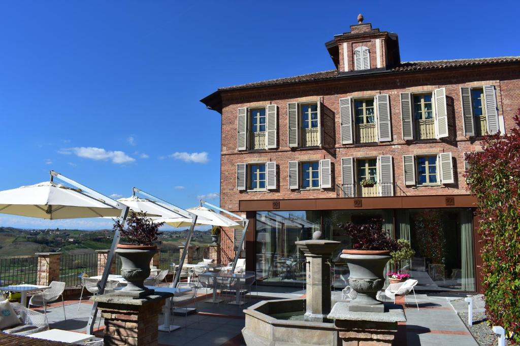 un bâtiment avec des tables et des parasols devant lui dans l'établissement Villa Fontana Relais Suite & Spa, à Agliano Terme