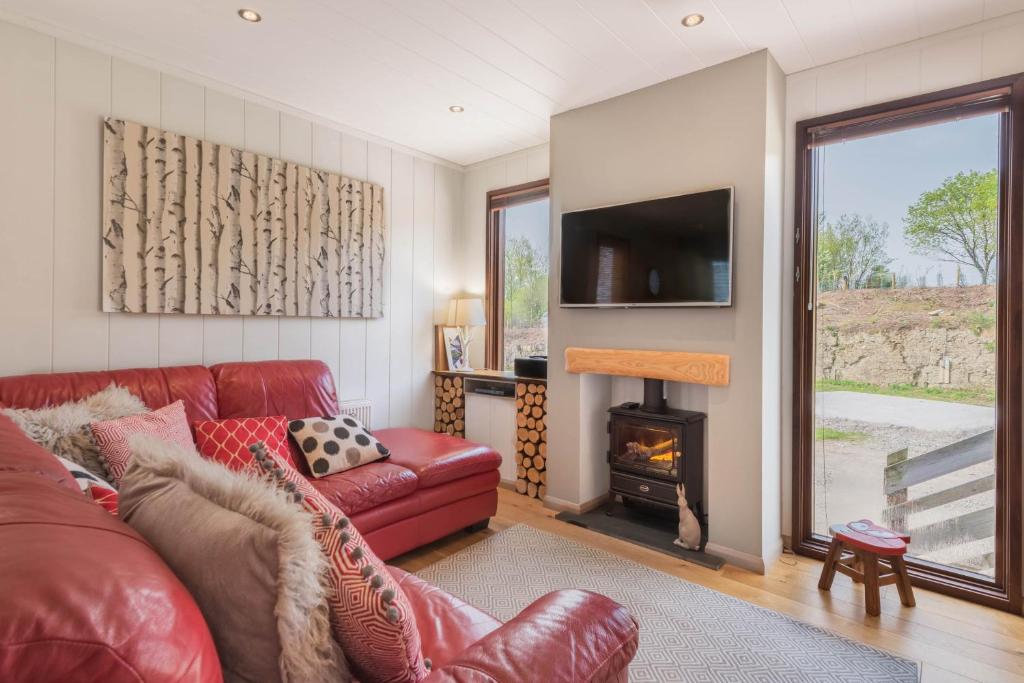 a living room with a red couch and a fireplace at Dobby Lodge in Bassenthwaite