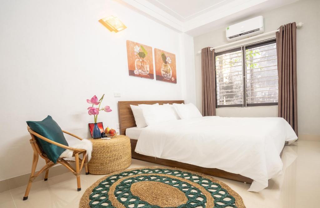 a bedroom with two beds and a chair and a window at Centre Alley House & Travel in Hanoi