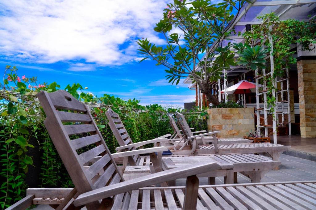 3 chaises en bois assises à côté d'un bâtiment dans l'établissement HOTEL ASRI CIREBON, à Cirebon