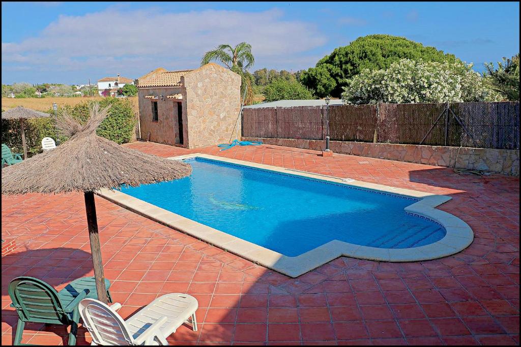 basen z 2 krzesłami i parasolem w obiekcie Apartamento con piscina comunitaria w mieście Conil de la Frontera