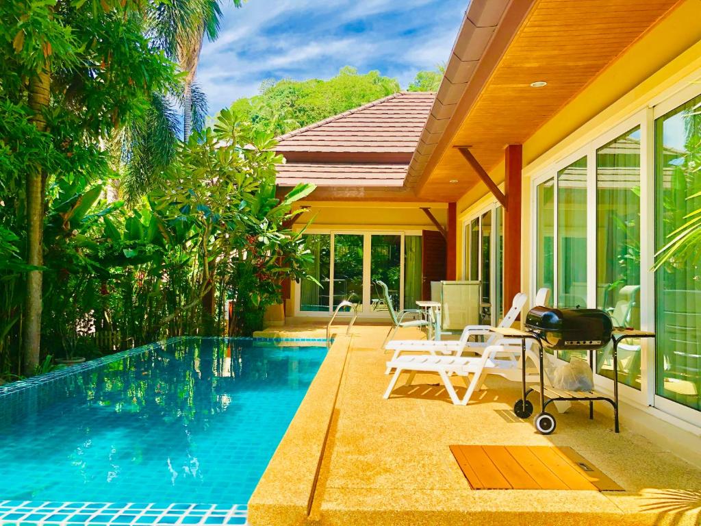 uma piscina com cadeiras e uma casa em Karon Pool Villa 卡伦3卧泳池别墅 em Praia de Karon