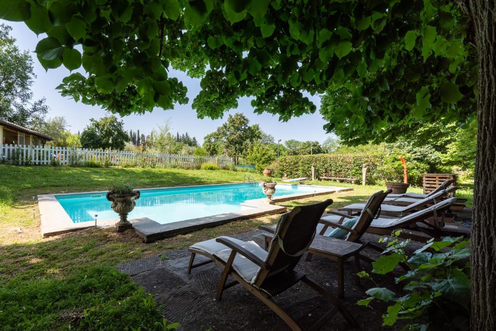 una piscina en un patio con sillas y un árbol en Villa il Rossignolo, en Grassina