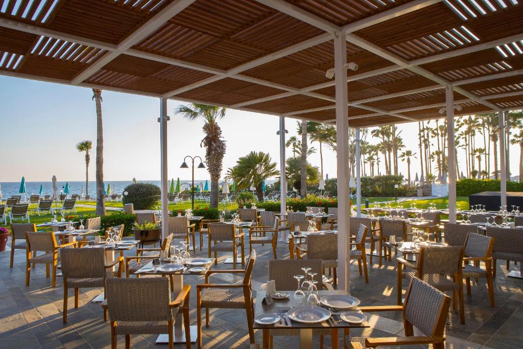 a restaurant with tables and chairs with the ocean in the background at Leonardo Cypria Bay in Paphos