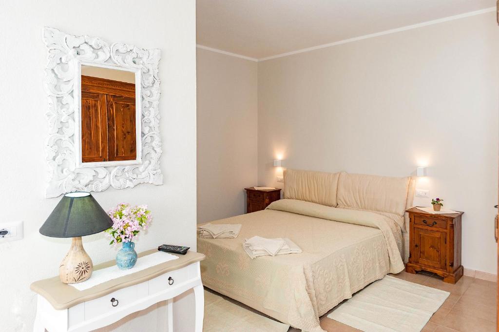 una camera da letto con un letto e uno specchio a parete di Lu Lioni Rooms a San Teodoro
