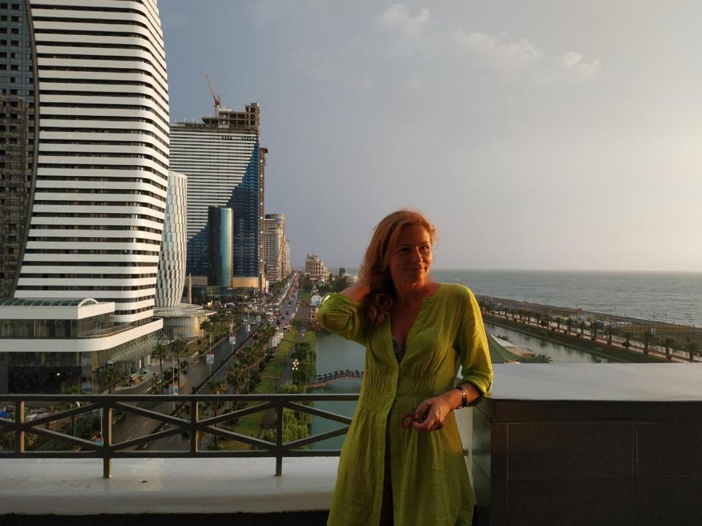 a woman in a green dress standing on a balcony at Apartment Miracle in Batumi
