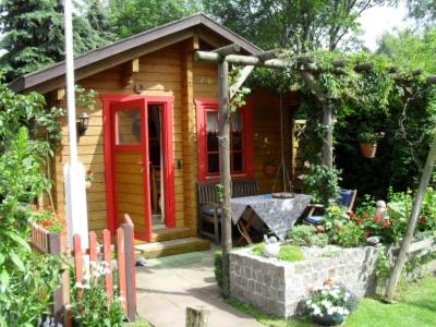 a small wooden cabin with red doors in a yard at Privatzimmer R. & R. Andersen in Lehnin